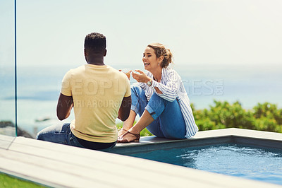 Buy stock photo Couple, poolside and drinking to talk in outdoor, bonding and together for love or joke. People, laughing and speaking on holiday or vacation, alcohol and trees or conversation for peace and calm