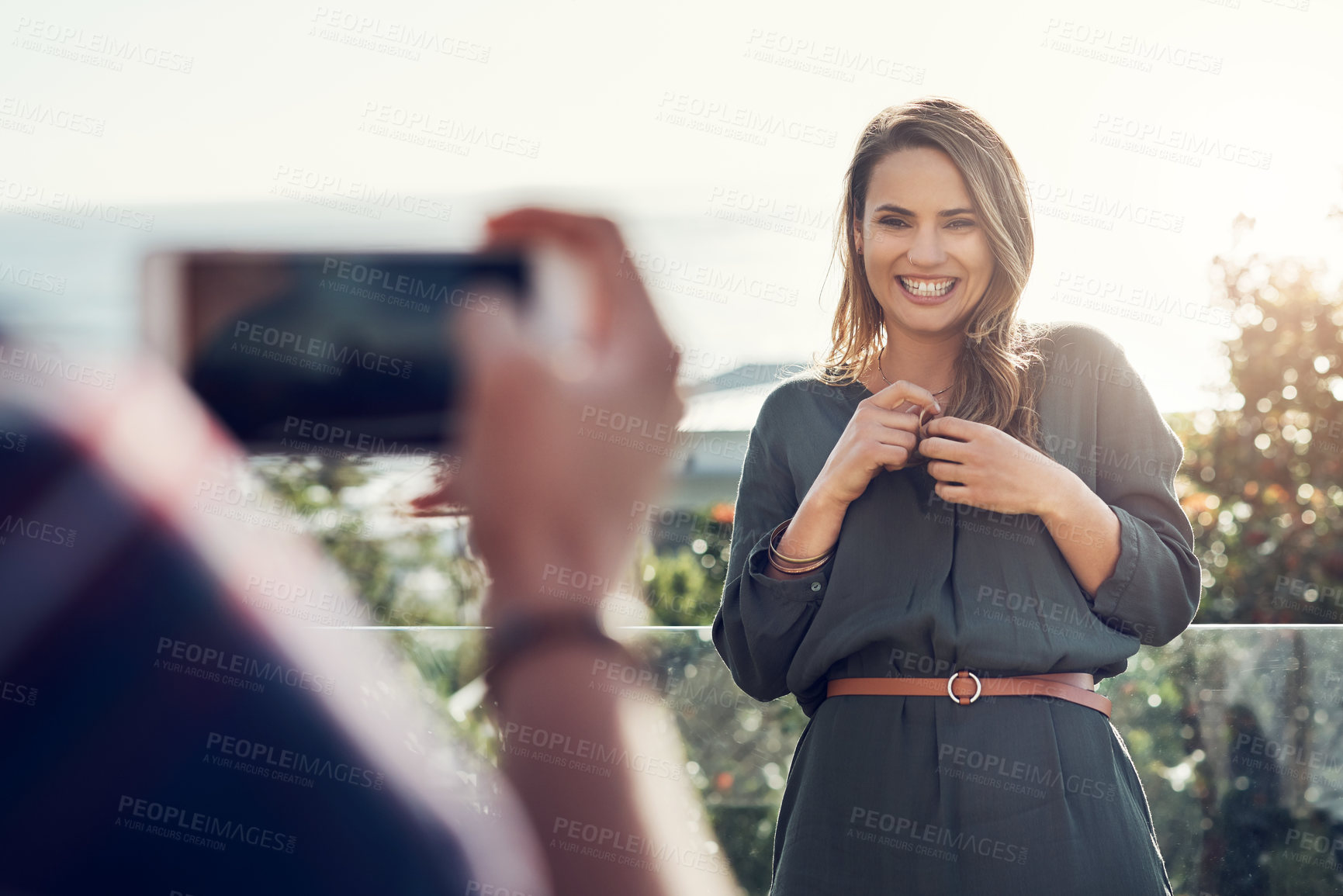 Buy stock photo Shot of an attractive young woman laughing while her boyfriend takes pictures of her outdoor