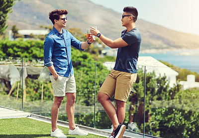 Buy stock photo Full length shot of two handsome young men having drinks and relaxing outdoors while on holiday