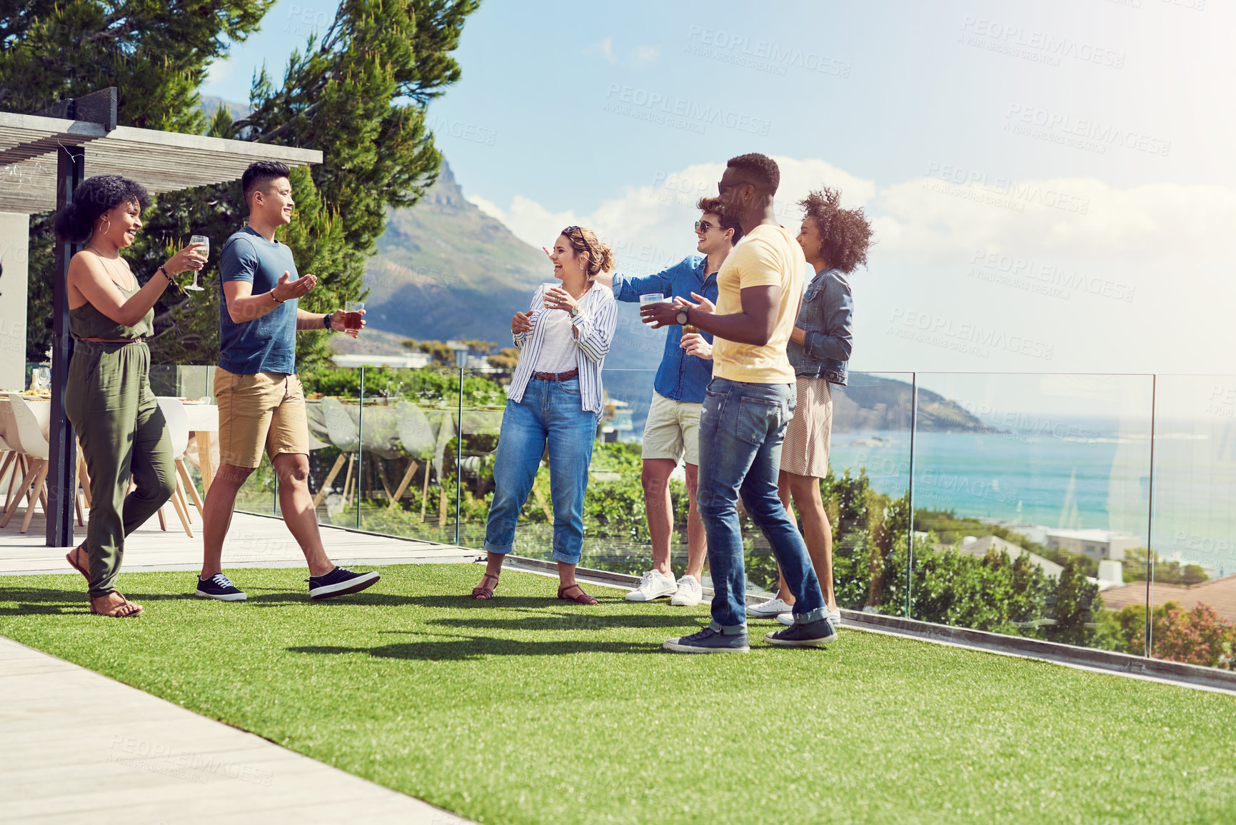 Buy stock photo Shot of a group of friends having drinks and enjoying themselves outdoors while on holiday