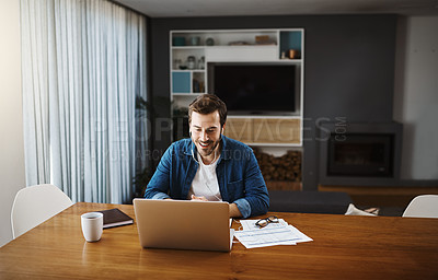 Buy stock photo Shot of a handsome young businessman sitting down and using his laptop to take a video call while working from home