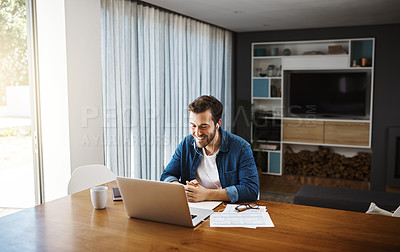 Buy stock photo Shot of a handsome young businessman sitting down and watching online videos on his laptop while working from home