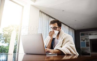 Buy stock photo Shot of a sickly young businessman blowing his nose with a tissue while working from home