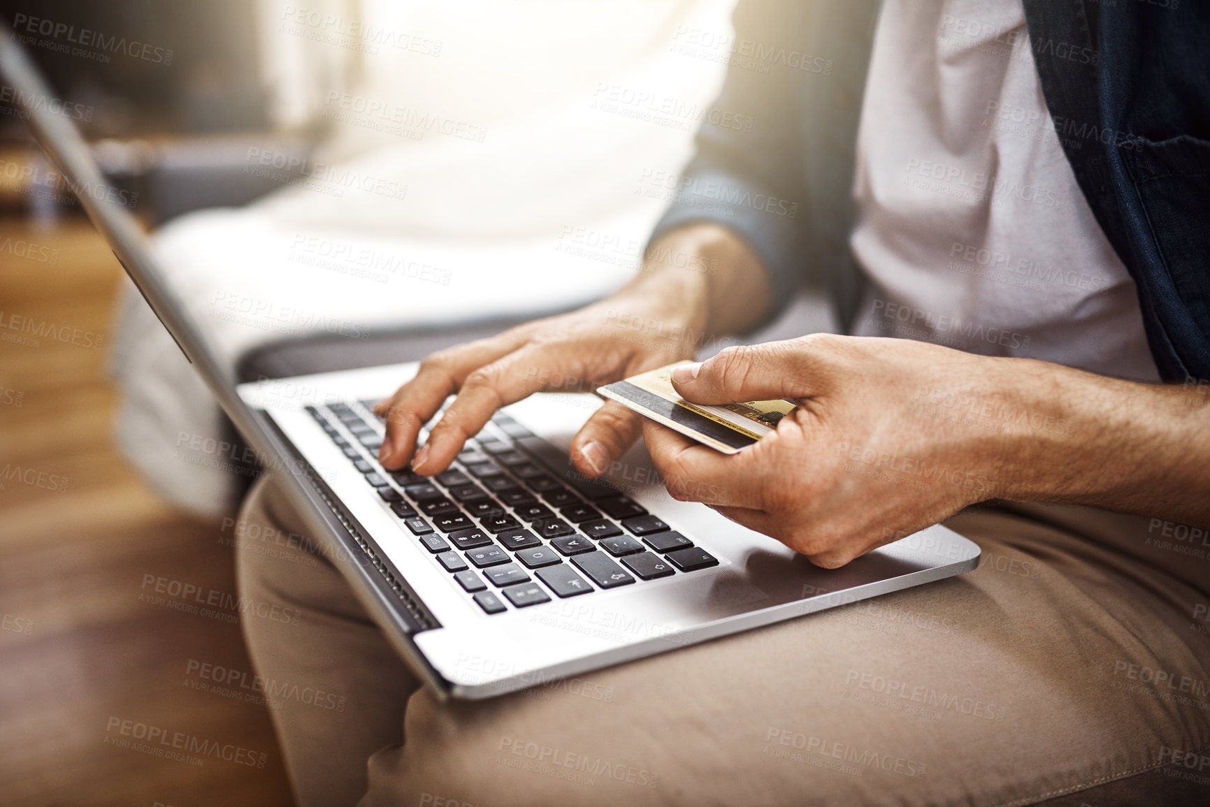 Buy stock photo Shot of an unrecognizable businessman sitting down and using his laptop to do some online shopping while working from home