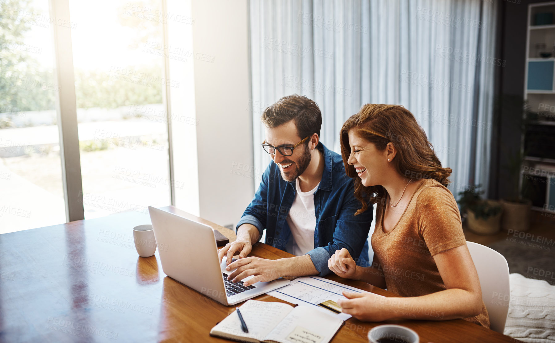 Buy stock photo Shot of a young couple doing some online shopping on a laptop together over the weekend at home