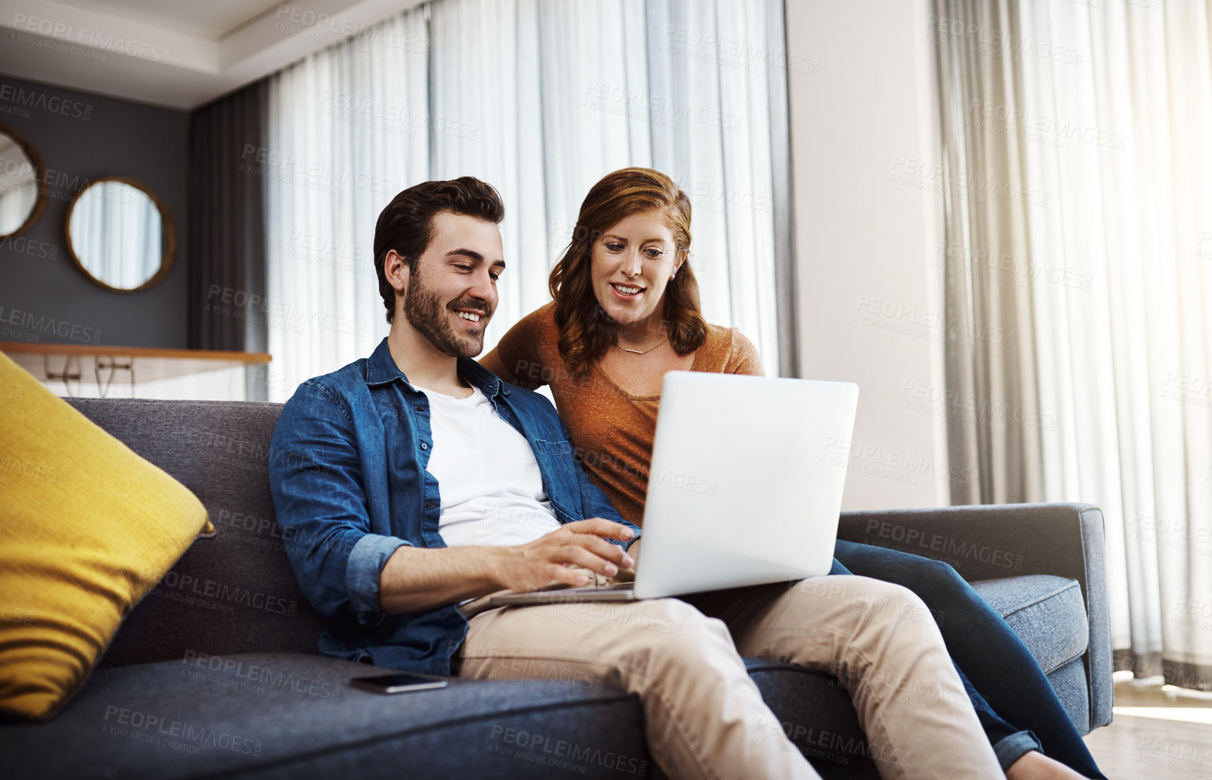 Buy stock photo Shot of a young couple doing some financial planning together on a laptop at home