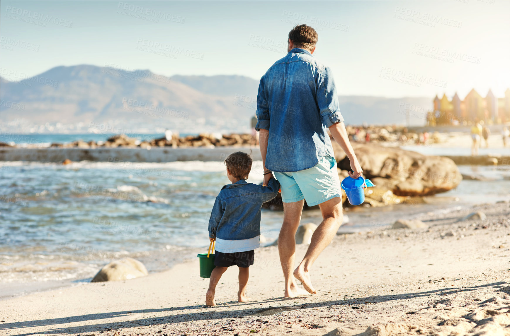 Buy stock photo Rearview shot of a father and his little son bonding together at the beach