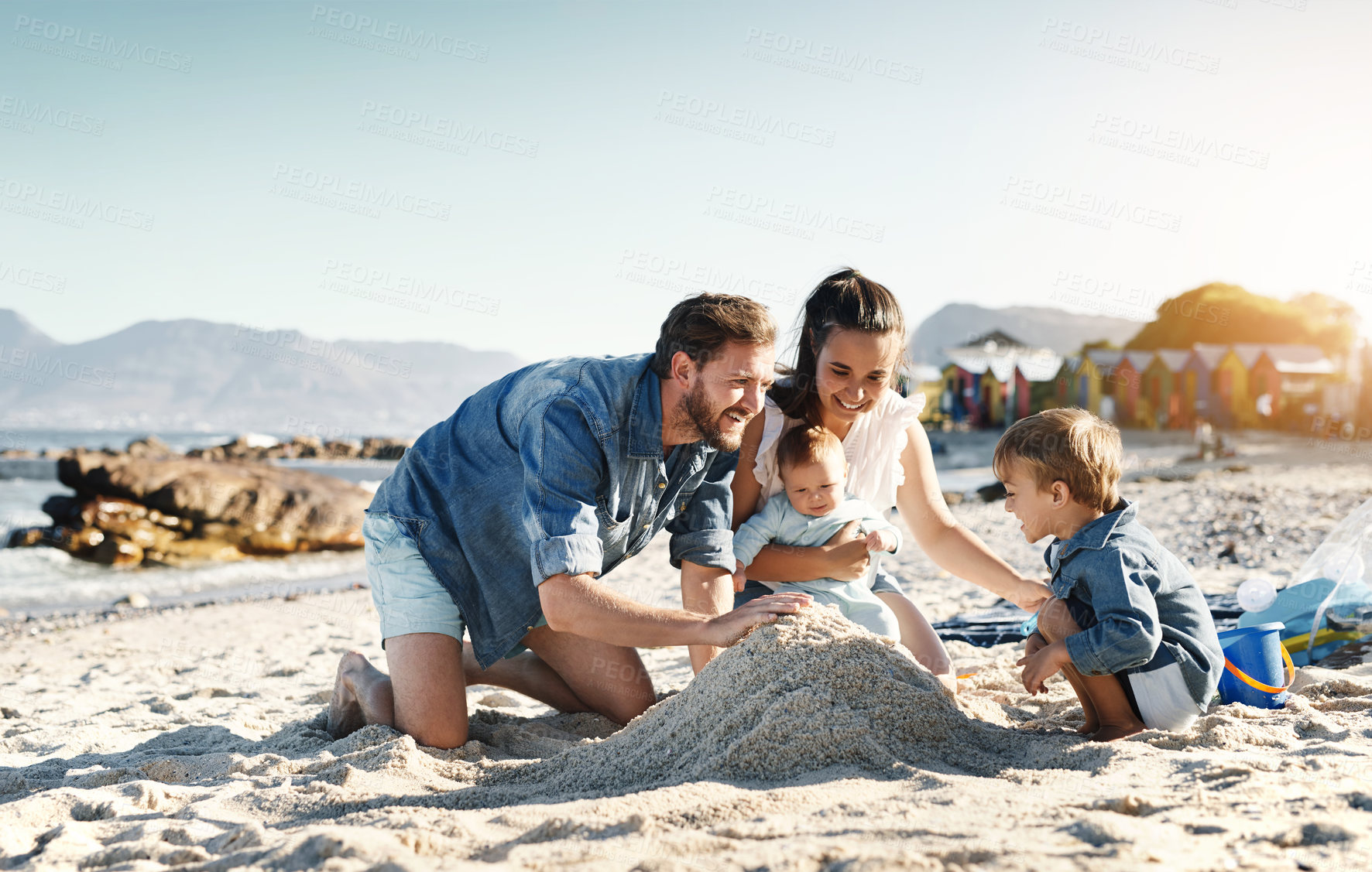 Buy stock photo Sandcastle fun, parents and children at the beach with bonding, love and support. Baby, mom and dad together with kids playing in the sun with happiness and smile by the ocean and sea with family