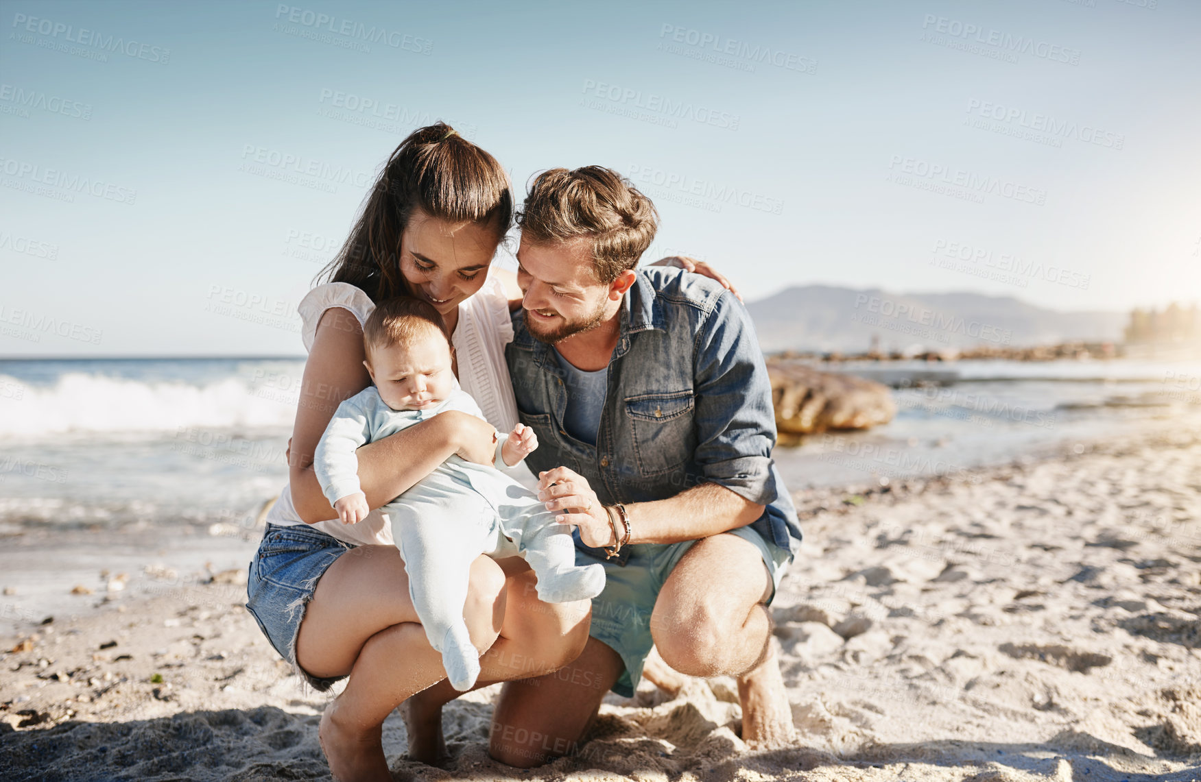 Buy stock photo Shot of parents bonding with their baby boy at the beach