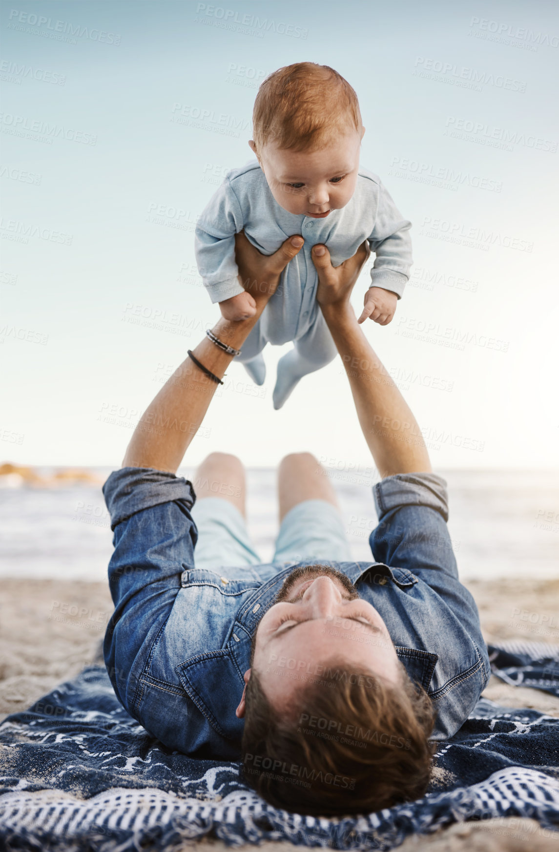 Buy stock photo Beach, sand and dad with lifting baby on towel for summer vacation, bonding and child development. Family, adventure and man with infant by ocean for fathers day, love and outdoor holiday in Florida