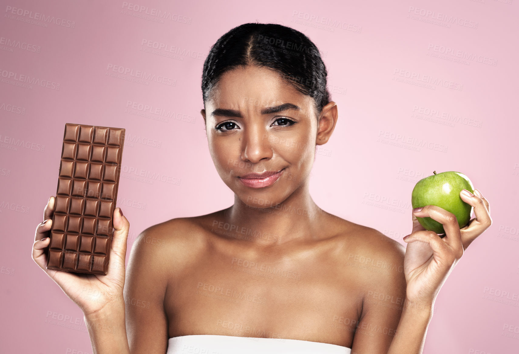 Buy stock photo Black woman, health and nutrition with food choice fro balanced diet isolated on pink background. Happy, female person or model and apple or chocolate option for weight loss fruit in studio.