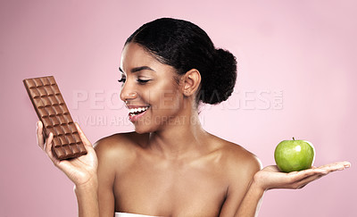 Buy stock photo Black woman, food choice and decision for balanced diet isolated on pink background. Happy, female person or model and smile for fruit or chocolate option on weight loss and wellness journey