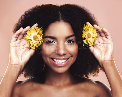 Buy stock photo Portrait of happy woman, hair care and beauty with yellow flowers on studio background. African model, natural skincare and daisy plants in afro for sustainable cosmetics, floral aesthetic and smile
