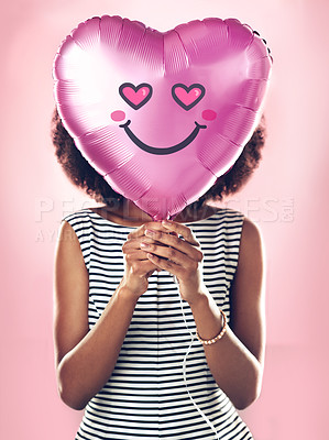 Buy stock photo Girl, emoji and black woman with balloon with heart for love, smile and covering face isolated on pink background. Abstract, gen z female person and icon for celebration, happy and by studio backdrop