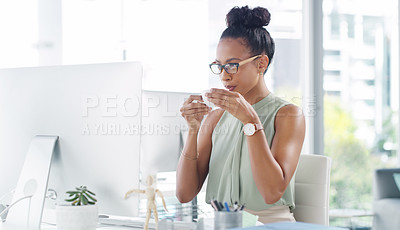 Buy stock photo Shot of an attractive young businesswoman having a cup of coffee while working at her desk in a modern office
