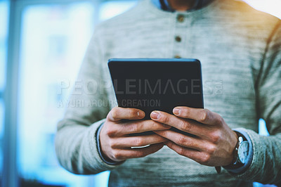 Buy stock photo Shot of an unrecognizable businessman using his digital tablet at work
