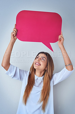 Buy stock photo Shot of an attractive young woman holding up a speech bubble against a blue background