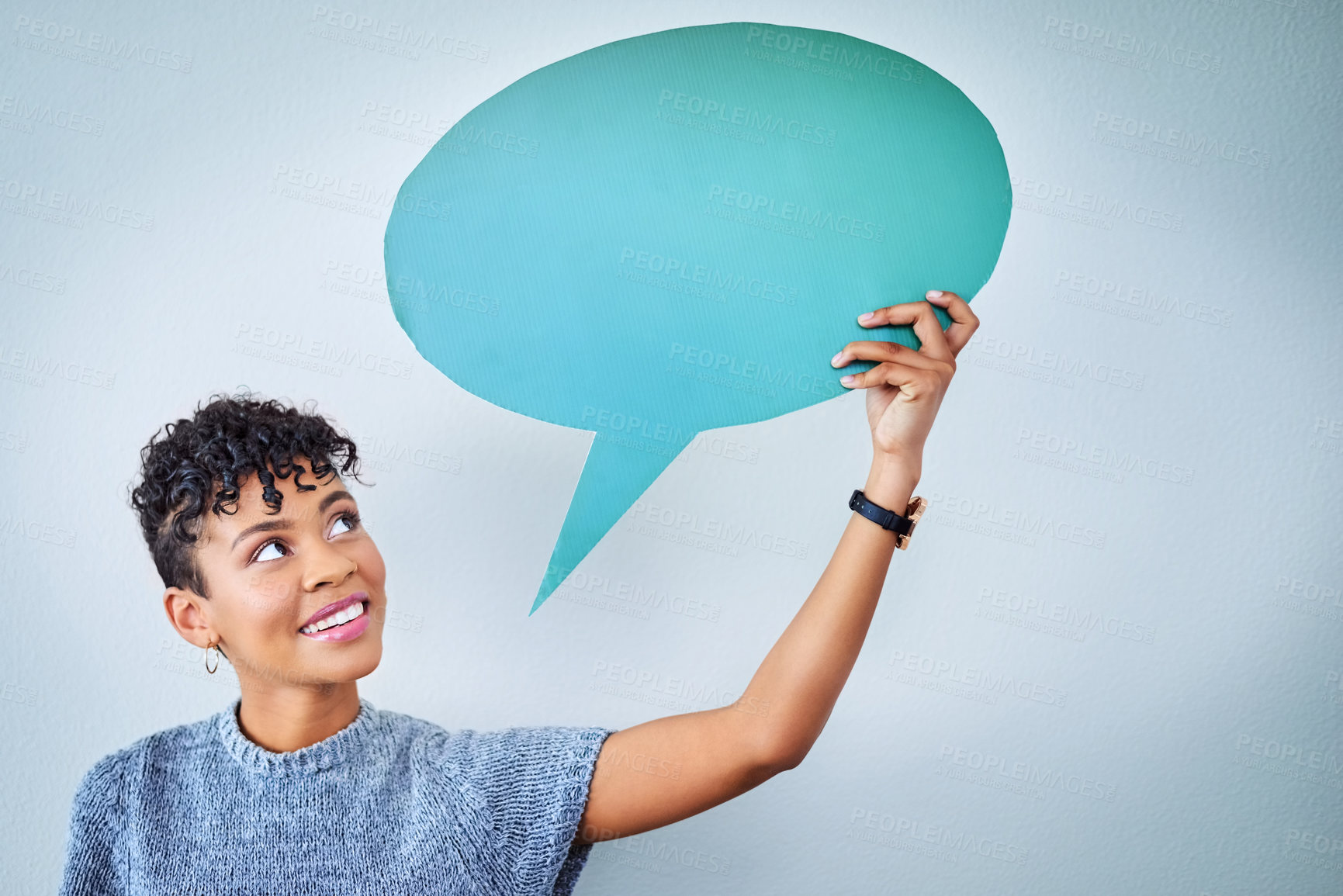 Buy stock photo Portrait of an attractive young woman holding up a speech bubble against a blue background