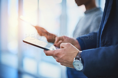 Buy stock photo Closeup shot of two unrecognizable businesspeople using their digital tablets during a meeting at work