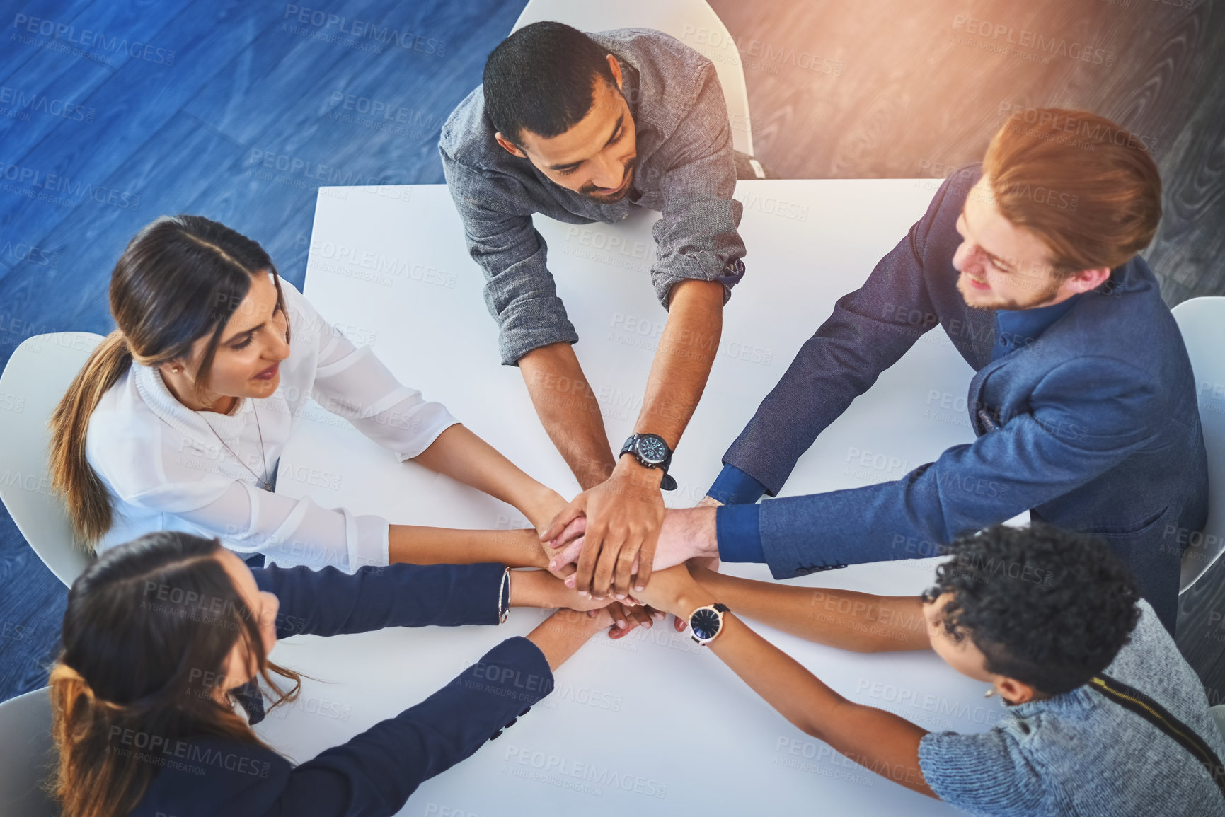 Buy stock photo High angle shot of a group of young businesspeople joining their hands together in unity during a meeting at work