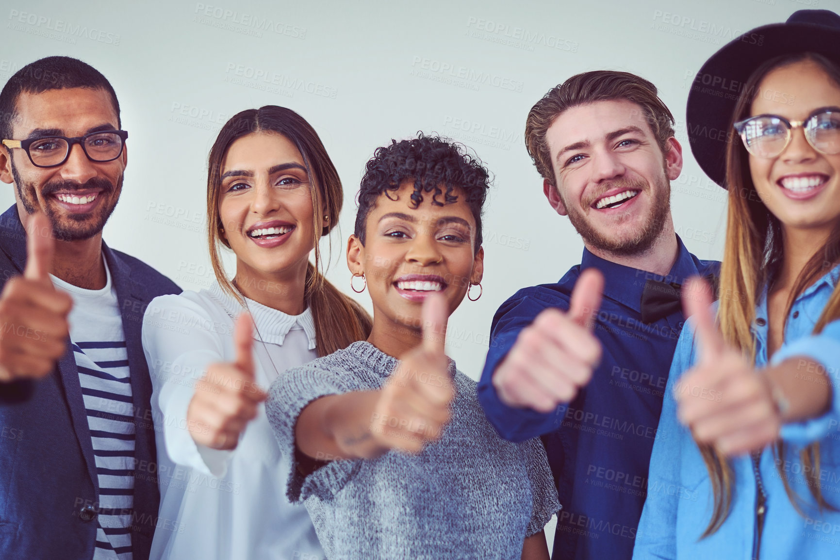 Buy stock photo Studio portrait of a group of young businesspeople showing thumbs up while standing against a grey background