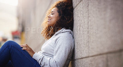 Buy stock photo Happy, relax and black woman by wall in city, urban town and street or lens flare by building in Houston, Texas. Earphones, student and gen z girl with smile for freedom, calm or listening to music