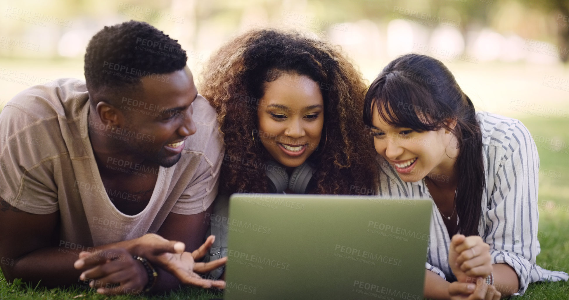 Buy stock photo Shot of a group of friends lying down and using a laptop together while