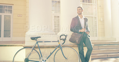 Buy stock photo Shot of a handsome young businessman posing next to a bicycle in the city