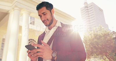 Buy stock photo Shot of a handsome young businessman using his cellphone while walking through the city