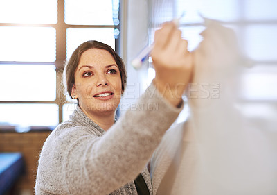 Buy stock photo Shot of a cheerful schoolteacher writing notes on a whiteboard in class