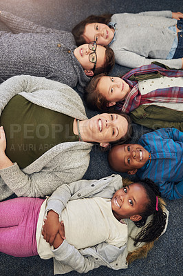 Buy stock photo Portrait of a group of elementary school kids and their teacher lying down on the floor in class