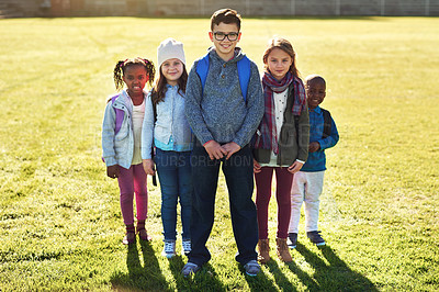 Buy stock photo Children, portrait and group on field at school with backpack, smile or pride for diversity with education. Kids, friends and happy on grass for learning, scholarship or future at academy in Canada