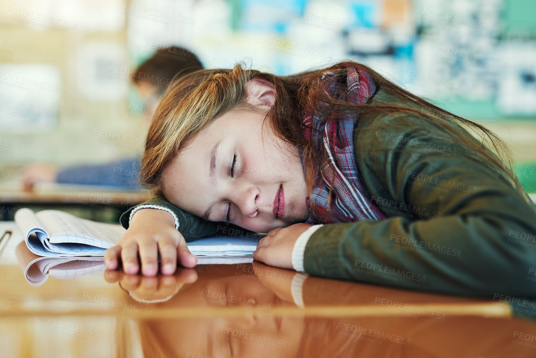 Buy stock photo Shot of an adorable elementary schoolgirl taking a nap on her desk in class
