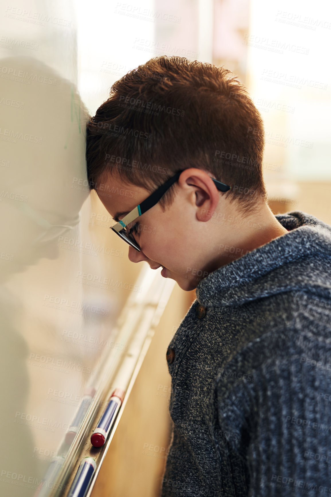 Buy stock photo Shot of an elementary school boy leaning with his head on the whiteboard in class