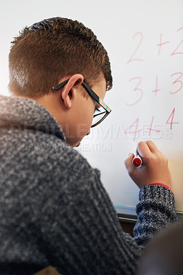 Buy stock photo Rearview shot of an elementary school boy writing on a whiteboard in class
