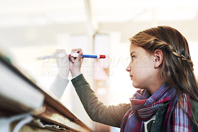 Buy stock photo Shot of an elementary school girl writing on a whiteboard in class