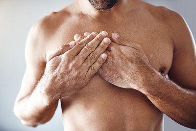 Buy stock photo Shot of a shirtless unrecognizable man holding his chest in pain while relaxing at home