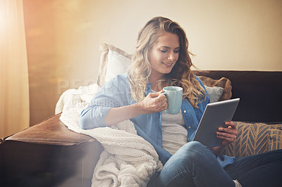 Buy stock photo Shot of a relaxed young woman having coffee and using a digital tablet on the sofa at home