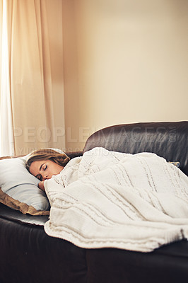 Buy stock photo Shot of a young woman sleeping peacefully on the sofa at home