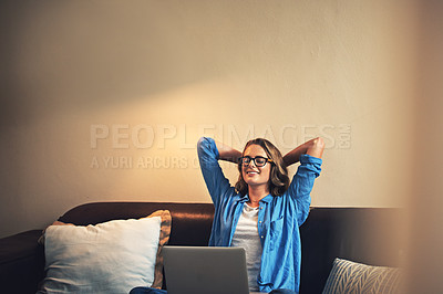 Buy stock photo Shot of a relaxed young woman using a laptop on the sofa at home