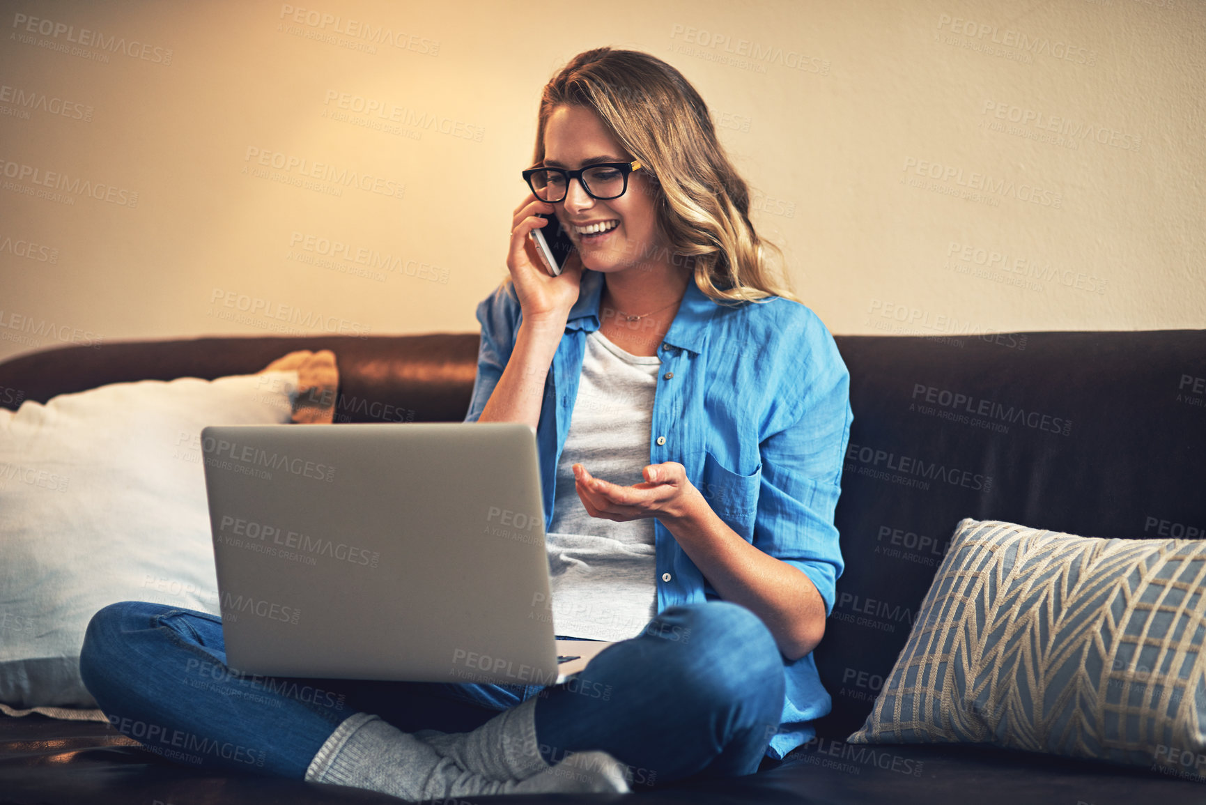 Buy stock photo Shot of a relaxed young woman using a laptop and smartphone on the sofa at home