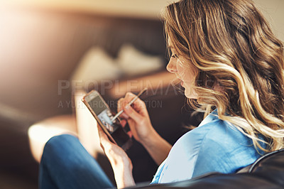 Buy stock photo Shot of a relaxed young woman using a smartphone and stylus on the sofa at home