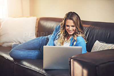 Buy stock photo Shot of a relaxed young woman using a laptop on the sofa at home