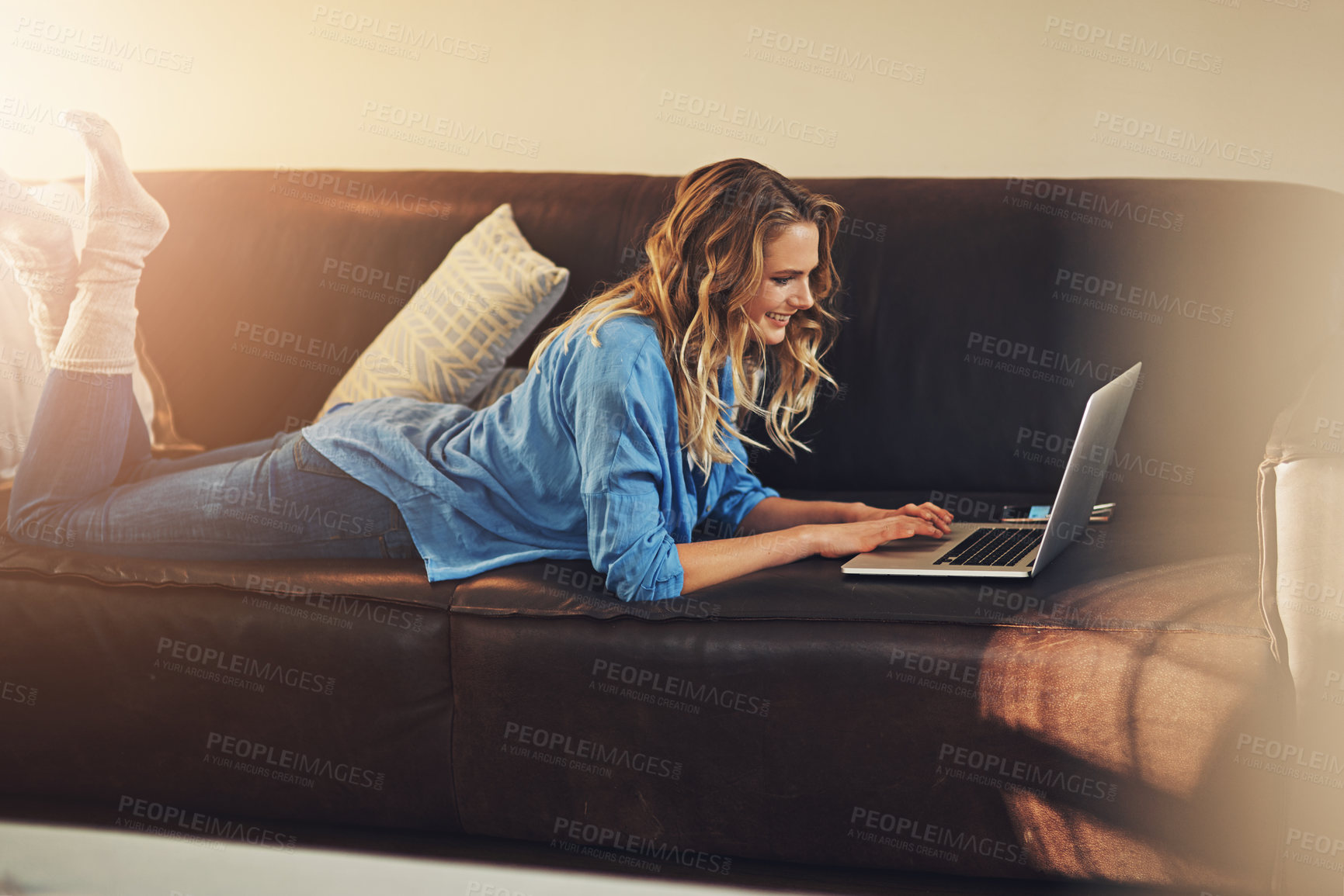 Buy stock photo Shot of a relaxed young woman using a laptop on the sofa at home