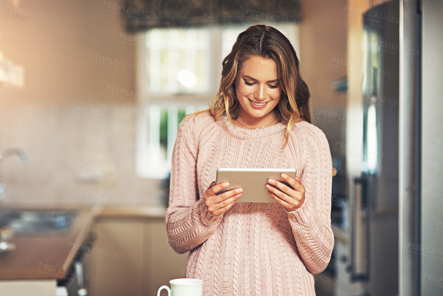 Buy stock photo Shot of a relaxed young woman having coffee and using a smartphone at home