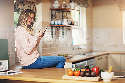 Buy stock photo Shot of a relaxed young woman having coffee and using a digital tablet at home