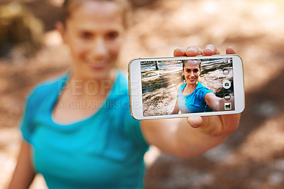 Buy stock photo Shot of a sporty young woman using her cellphone while out in nature