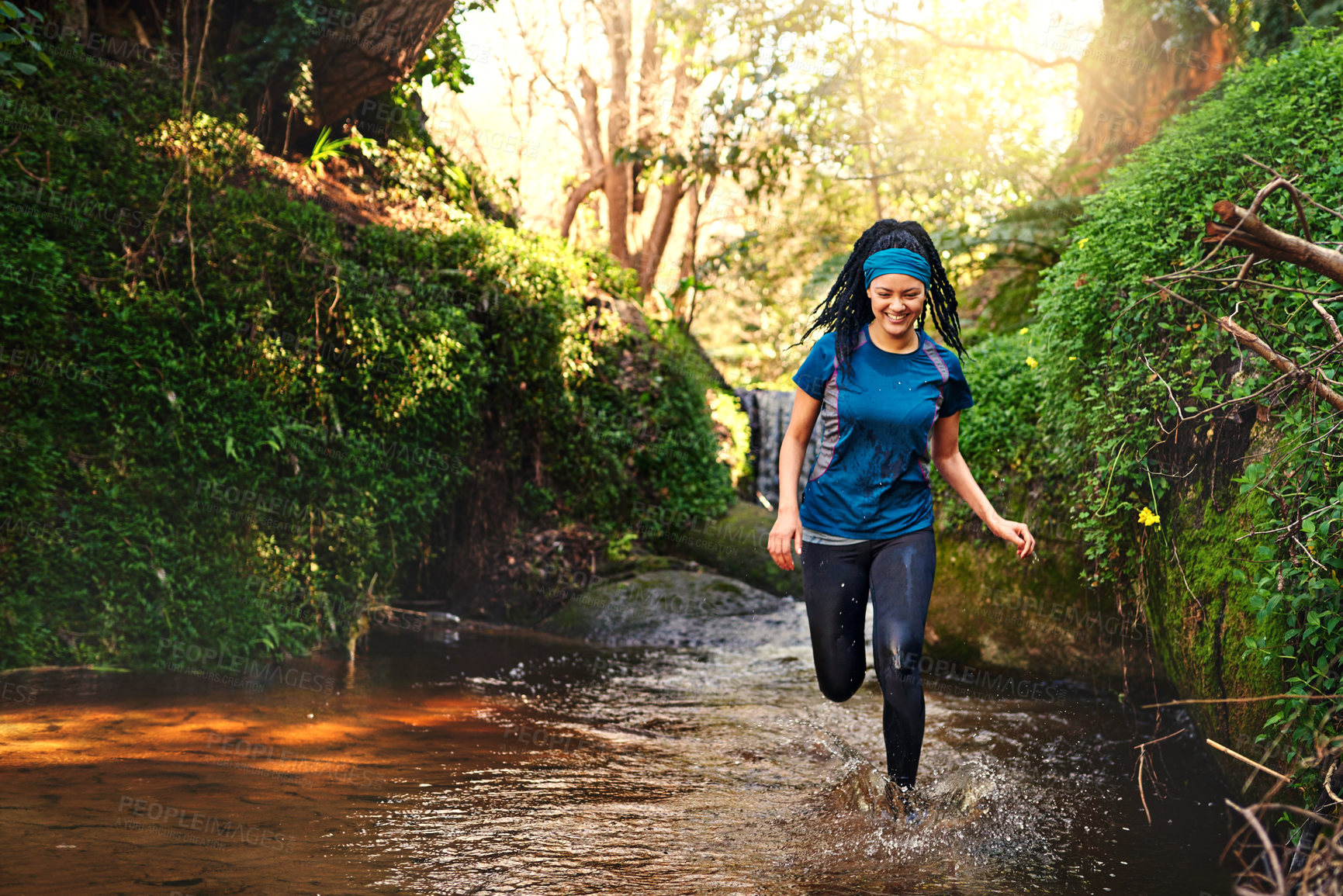 Buy stock photo Shot of a sporty young running through a stream of water in nature