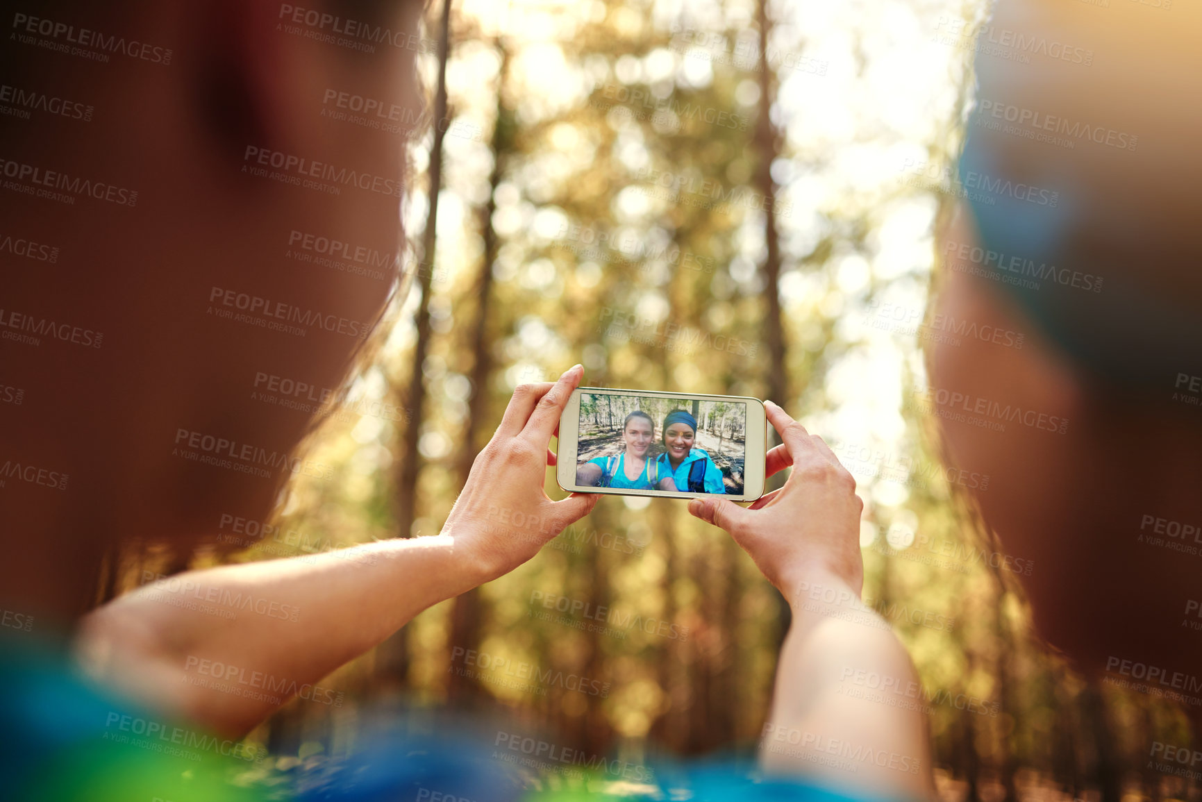 Buy stock photo Shot of two sporty young woman taking pictures while out in nature
