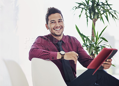 Buy stock photo Cropped portrait of a handsome young businessman smiling while holding a digital tablet in a modern office